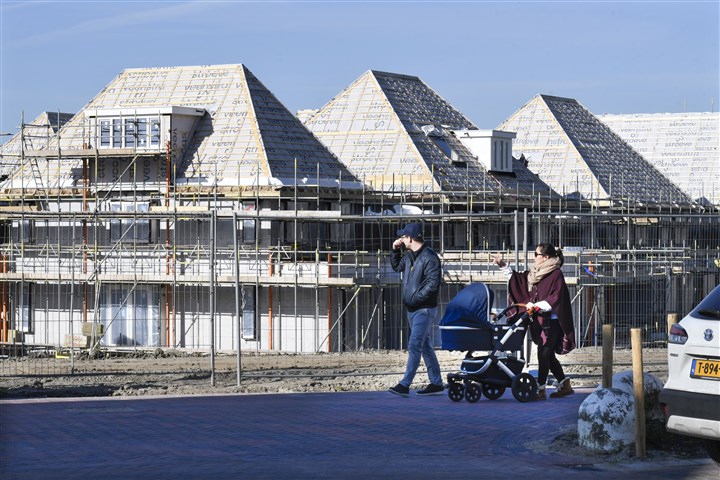 Een gezin met kinderwagen lopen door een nieuwbouwwijk heen.