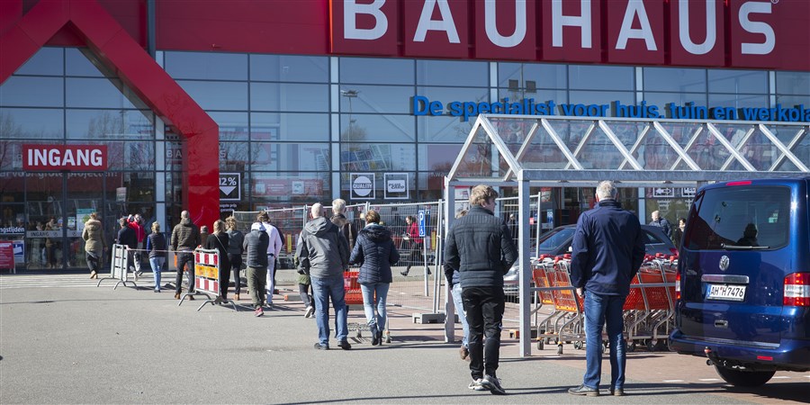 Bezoekers staan ivm corona op afstand van elkaar bij ingang van bouwmarkt te wachten